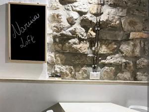 a stone wall with a sign in front of a bench at Narnia Loft in Narni