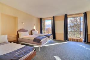 ein Hotelzimmer mit 2 Betten und großen Fenstern in der Unterkunft Hôtel Restaurant Bellevue in Onnens