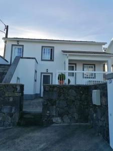 a white house with a stone fence in front of it at Casa da Isabel in São Roque do Pico