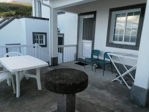 a patio with a white table and chairs on a balcony at Casa da Isabel in São Roque do Pico