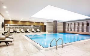 a large swimming pool in a hotel lobby with chairs at Divan Gaziantep in Gaziantep