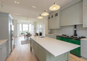 a kitchen with green and white cabinets and a table at Ryvra in North Berwick