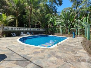 een zwembad in een tuin met palmbomen bij Loft Praia Brava - Suíte com Área Gourmet Privativa in Ubatuba