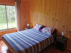 Un dormitorio con una cama con una manta azul y blanca. en Alojamientos doña Inés, en Pucón