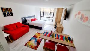 sala de estar con sofá rojo y silla roja en Toscana LOFT - Apartasuites, en Bogotá