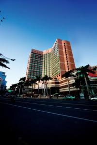 a large building with palm trees in front of a street at New World Shunde Hotel in Shunde