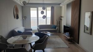 Temi's Apartments 2 في إسكوبية: غرفة معيشة مع طاولة وكراسي وتلفزيون