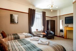a hotel room with two beds and a television at Tanes Hotel in Cardiff