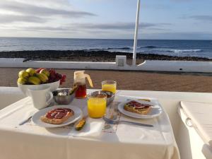 a table with food and drinks on a table with the ocean at El Mar de Peyo , primera línea de playa in Playa Honda