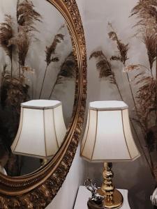 duas lâmpadas sentadas numa mesa em frente a um espelho em Cesis Boulevard Apartments em Cēsis