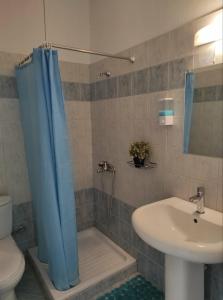 a bathroom with a blue shower curtain and a sink at Hotel Ilios in Kriopigi