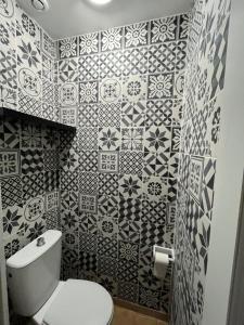 bagno con servizi igienici bianchi e piastrelle bianche e nere. di Maison proche de l'aéroport CDG-Paris a Goussainville
