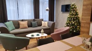 een woonkamer met een kerstboom en een bank bij Erdőalja 11 Apartman in Nyíregyháza