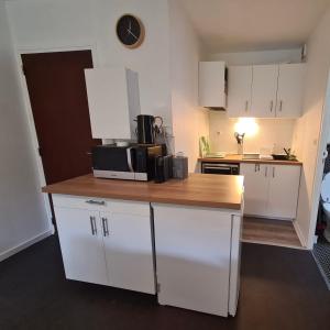 a kitchen with white cabinets and a wooden counter top at Très joli appartement 4-6 personnes dans Luchon in Luchon