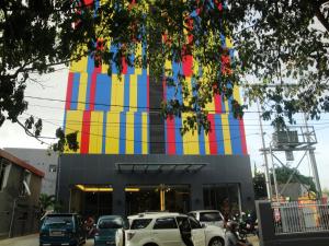 kolorowy budynek z samochodami zaparkowanymi przed nim w obiekcie Top Hotel Manado by Gran Puri w mieście Manado
