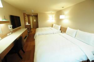 a hotel room with two beds and a television at Kindness Hotel - Kaohsiung Main Station in Kaohsiung