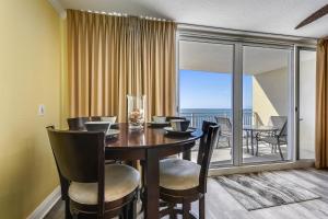 a dining room with a table and chairs and a balcony at Emerald Beach #1227 by Book That Condo in Panama City Beach