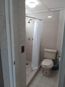 a bathroom with a toilet and a shower with a shower curtain at Hotel Duve Coral in Loreto