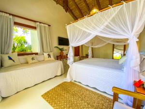 a bedroom with two white beds and a window at Pousada Recanto Caxando in Trancoso