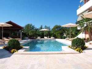 a swimming pool in a resort with chairs and umbrellas at Apartments Villa Učka in Opatija