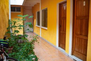 a yellow building with a door and a plant at Natz Hotel in Flores