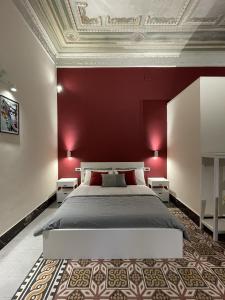 パレルモにあるArricría Room Suiteの赤い壁のベッドルーム1室(大型ベッド1台付)