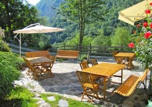 a patio with wooden tables and chairs and an umbrella at Gîte La Grange au Bois in Viella +30 photos