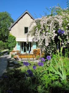 a house with benches and flowers in front of it at Gîte La Grange au Bois in Viella