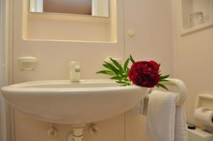 a bathroom with a white sink with a red rose on it at Gästehaus Bernhard in Lochau