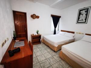 a room with two beds and a table with a laptop at Natz Hotel in Flores