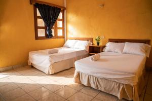two beds in a room with a window at Natz Hotel in Flores