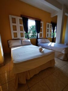 a bedroom with two beds and a window at Natz Hotel in Flores