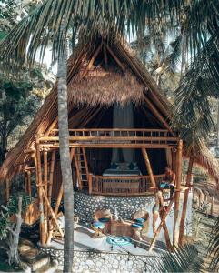 a thatchamboo hut with a man sitting in front of it at La royale Romantic Bamboo Villas in Klungkung