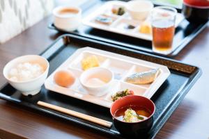 two plates of food on a black tray with chopsticks at Grampus Sea in Shirahama