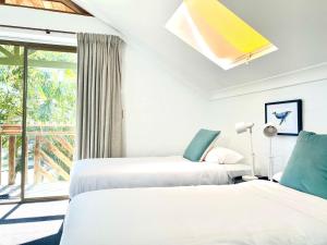 two beds in a room with a window at Byron Bay Accom Gilmore Court 4 in Byron Bay