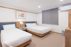 a bedroom with two beds and a window and a chalkboard at Blue Ocean Motel Apollo Bay in Apollo Bay