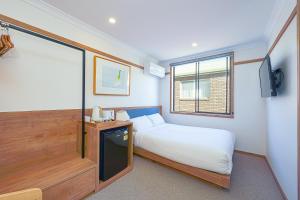 ein kleines Schlafzimmer mit einem Bett und einem Fenster in der Unterkunft Blue Ocean Motel Apollo Bay in Apollo Bay