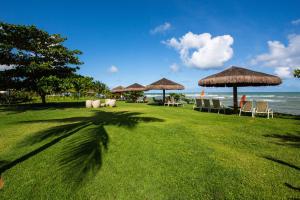 a lawn with umbrellas and chairs on the beach at GUARAJUBA Condomínio PARAÍSO DOS CORAIS BEACH RESORT 132 in Guarajuba