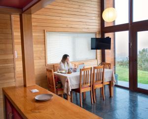 a woman sitting at a table in a room at Cabañas Tungulú in Puerto Montt