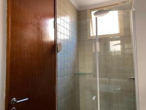 a bathroom with a shower with a glass door at Apartamento Enseada in Guarujá