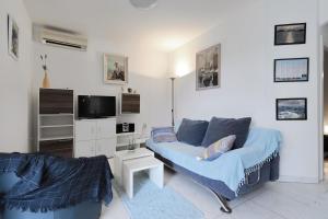 un salon avec un canapé bleu et une télévision dans l'établissement Apartments Djurdja - 20 m from beach, à Murter