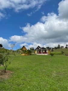 a green field with two houses in the distance at Campamento SacBé in Ocosingo
