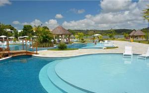 a pool at a resort with chairs and umbrellas at ILOA Ap inteiro - 2 suites sala cozinha in Barra de São Miguel