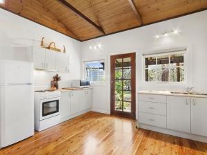 a kitchen with white cabinets and a wooden ceiling at Blue Apple Lodge in Bilpin