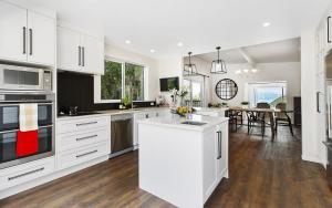 a kitchen with white cabinets and a dining room at Whitby sea view in Porirua