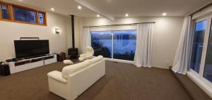 een woonkamer met een witte bank en een flatscreen-tv bij Whitby sea view in Porirua
