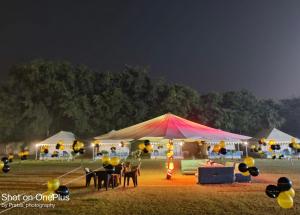 a tent with a table and chairs in a field at Agra Camps and Resort in Agra