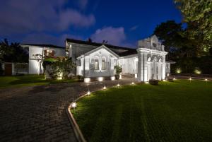 a white house with lights on a lawn at night at Maniumpathy Hotel in Colombo