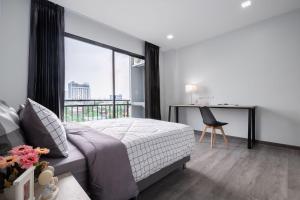 una camera con letto e scrivania con finestra di Aqua Residences อควา เรสซิเดนซ์ ห้องพักใหม่ให้เช่า ติดรถไฟฟ้าสถานีวุฒากาศ a Thonhuri