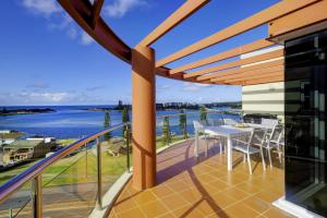 a balcony with a table and chairs and a view of the water at Sunrise Luxury Apartments in Tuncurry